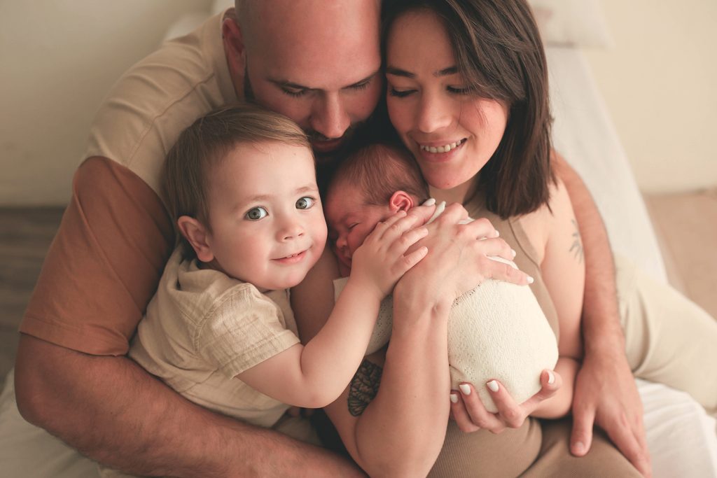 Familia abrazándose: madre, padre y bebé juntos en un momento tierno.